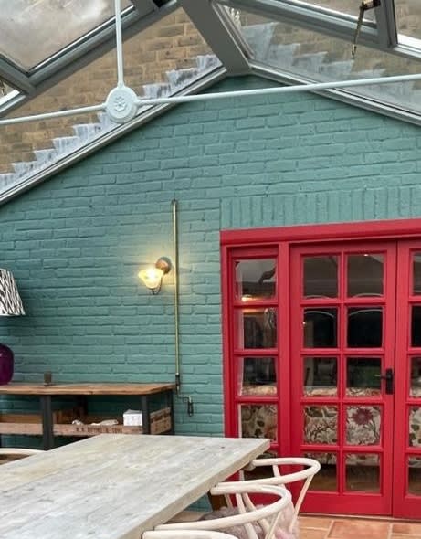 Teal-painted brick wall with red French doors in a conservatory