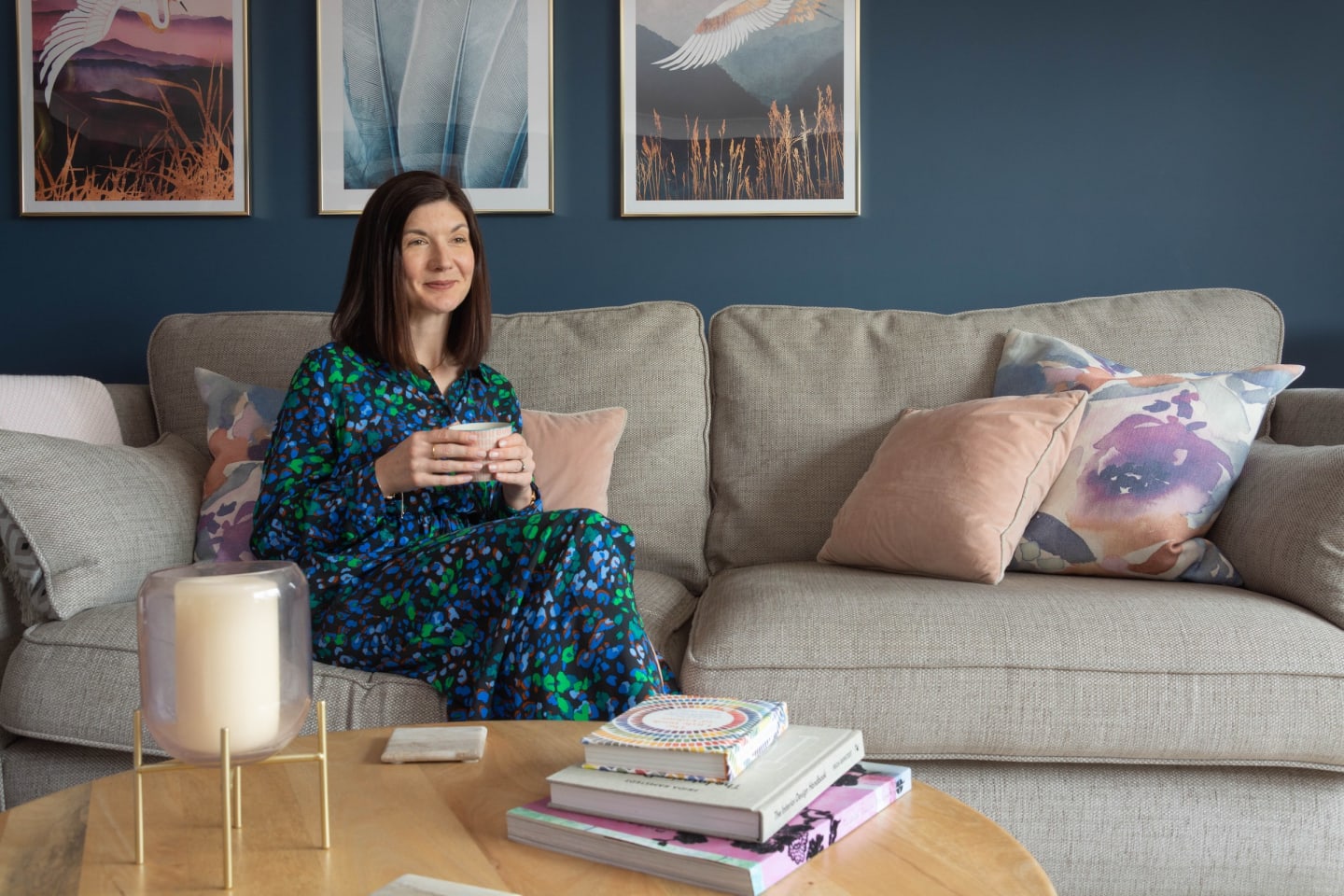Emma Downie sitting in blue living room with blush pink and brass accents.