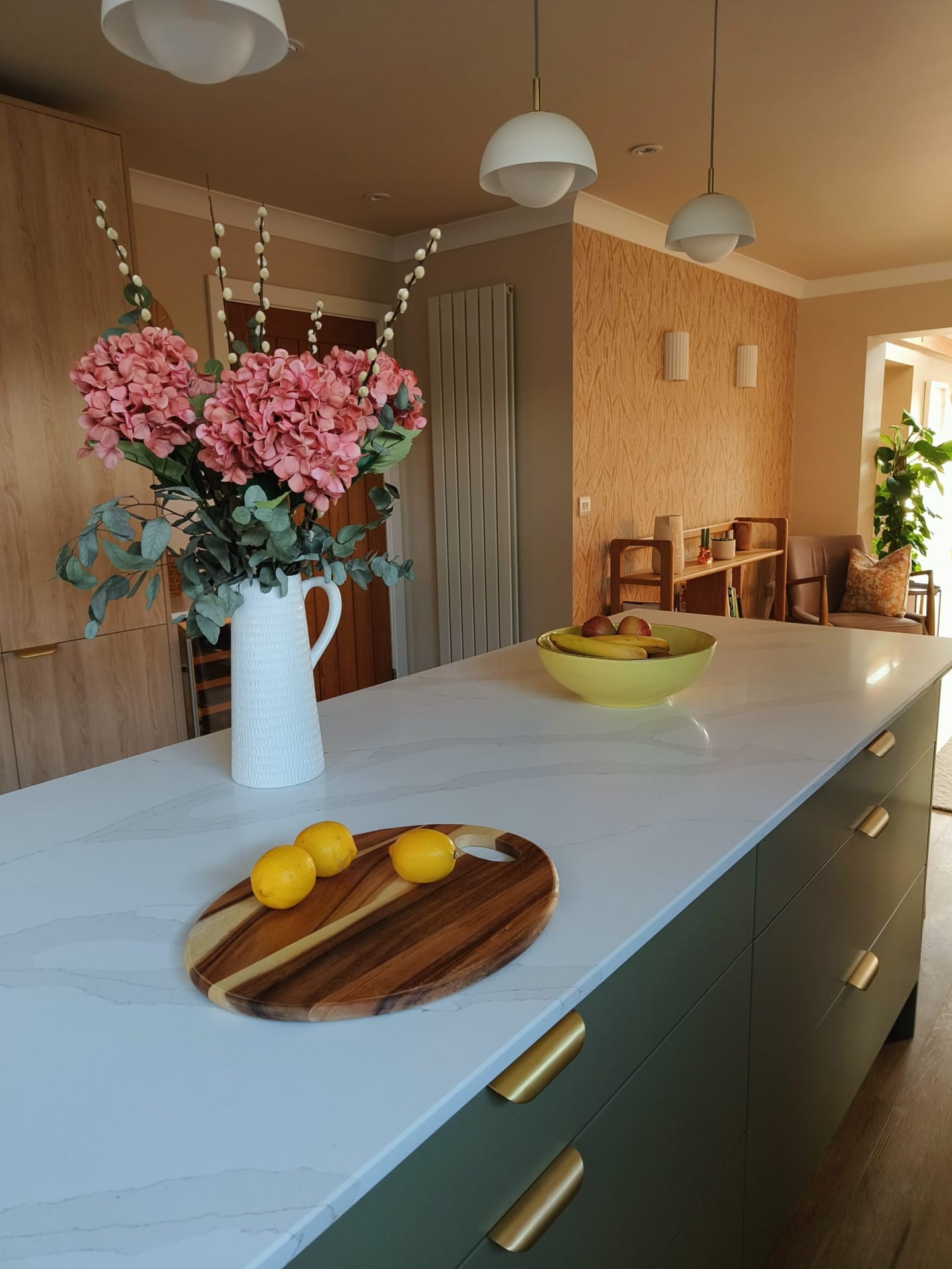 Marbled quartz worktop with pink hydrangeas in a jug and brass cupboard handles
