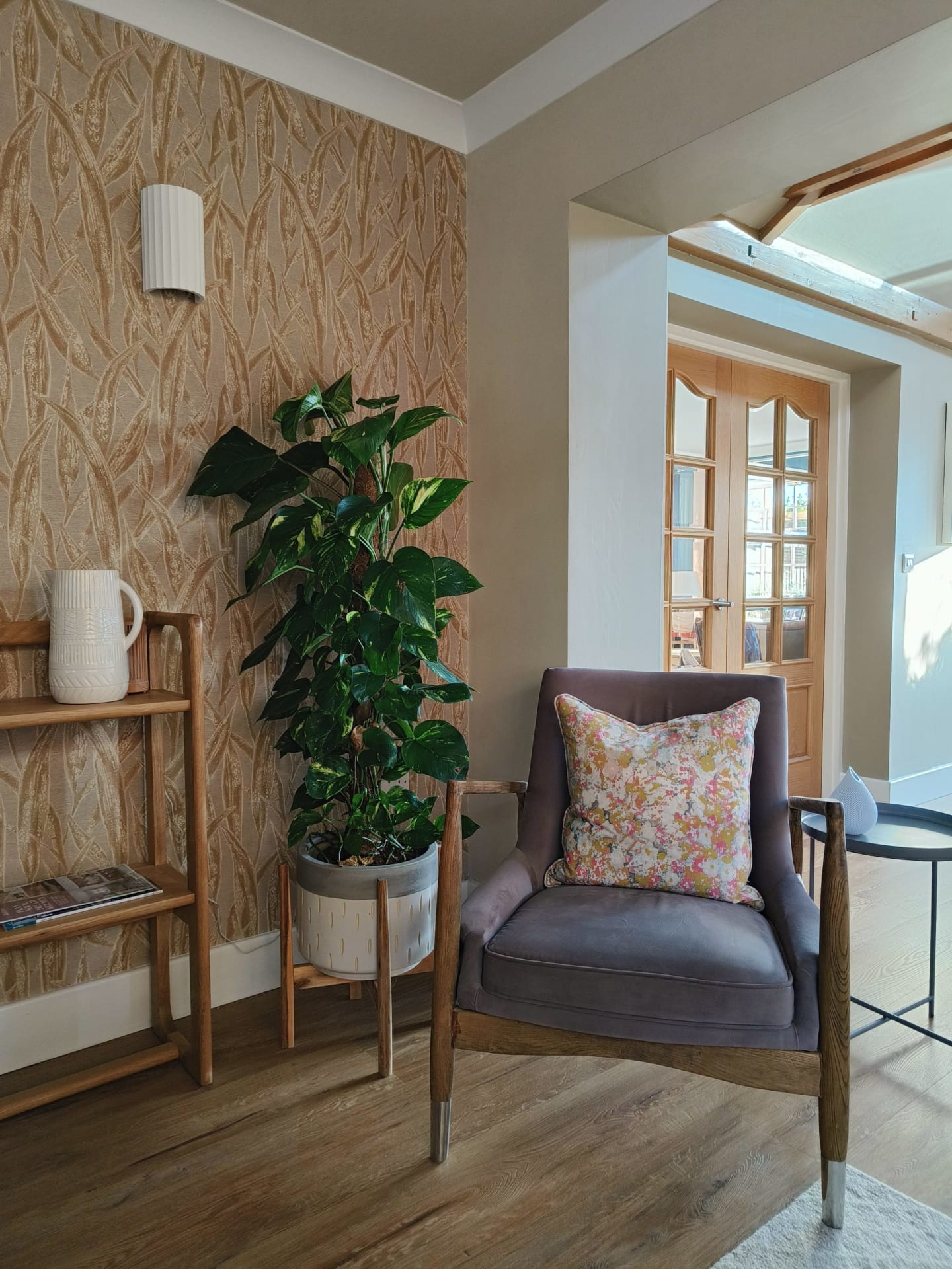 Plum velvet armchair against textured grasscloth wallpaper with a large houseplant