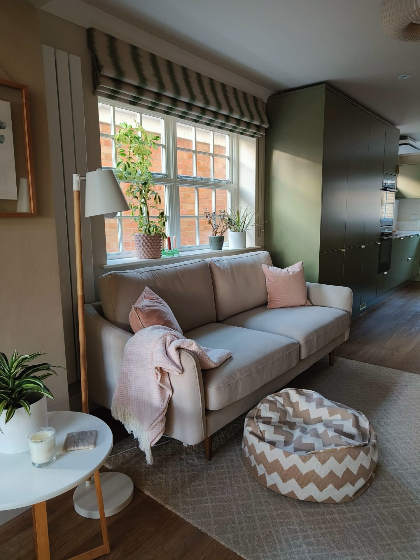 Snug with a grey sofa, striped roman blind, pink throw and zigzag patterned pouffe