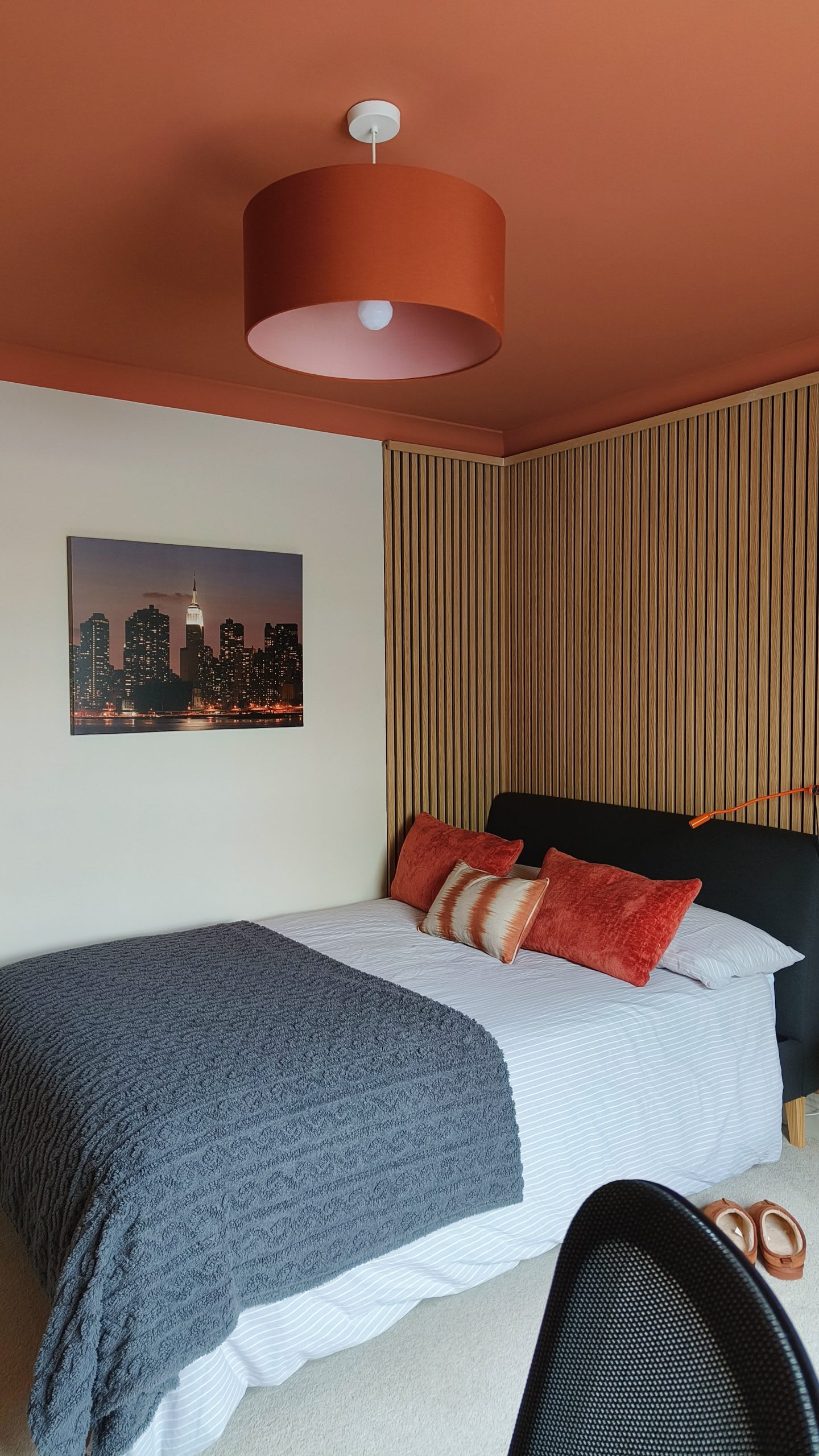 Bedroom with terracotta ceiling, oak slat panelling and a New York skyline canvas