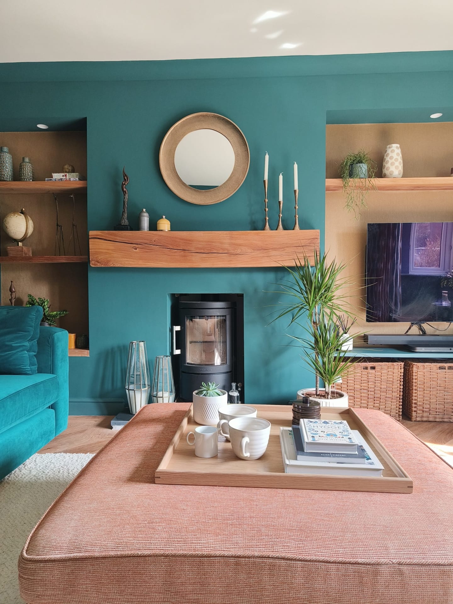 Oak mantel in teal living room with gold wallpaper alcoves