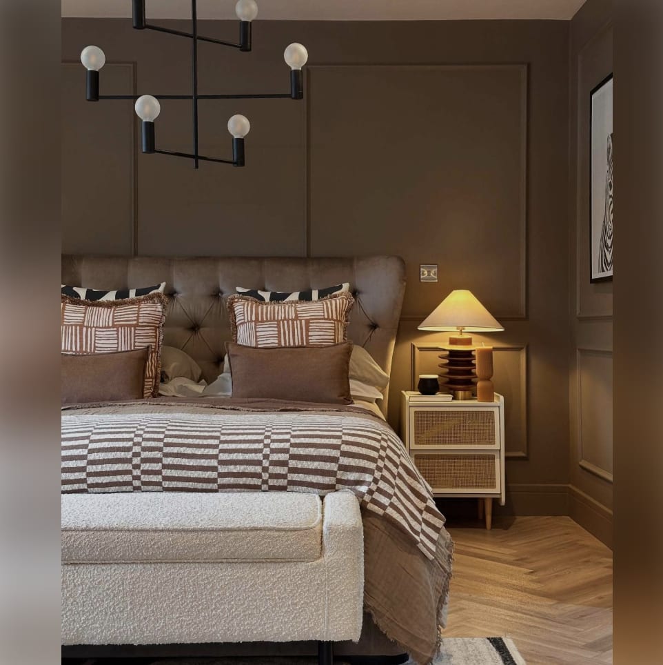 Chocolate brown panelled bedroom with a tufted headboard, striped bedding and a cream bench