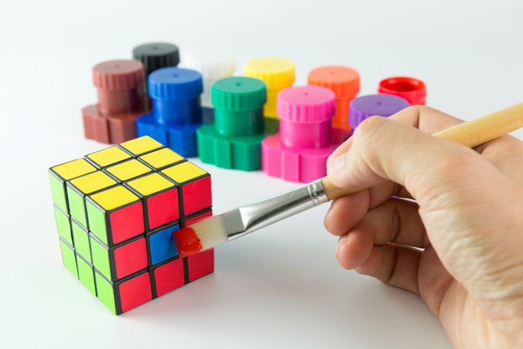 Person cheats to complete a rubik cube by painting a blue square red to emphais how attempting to shortcut the process of adopting okrs was a mistake.