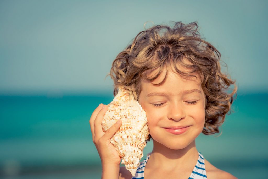 Child listens to a conch shelf to emphasis the need to listen and learn during the process of adopting OKRs