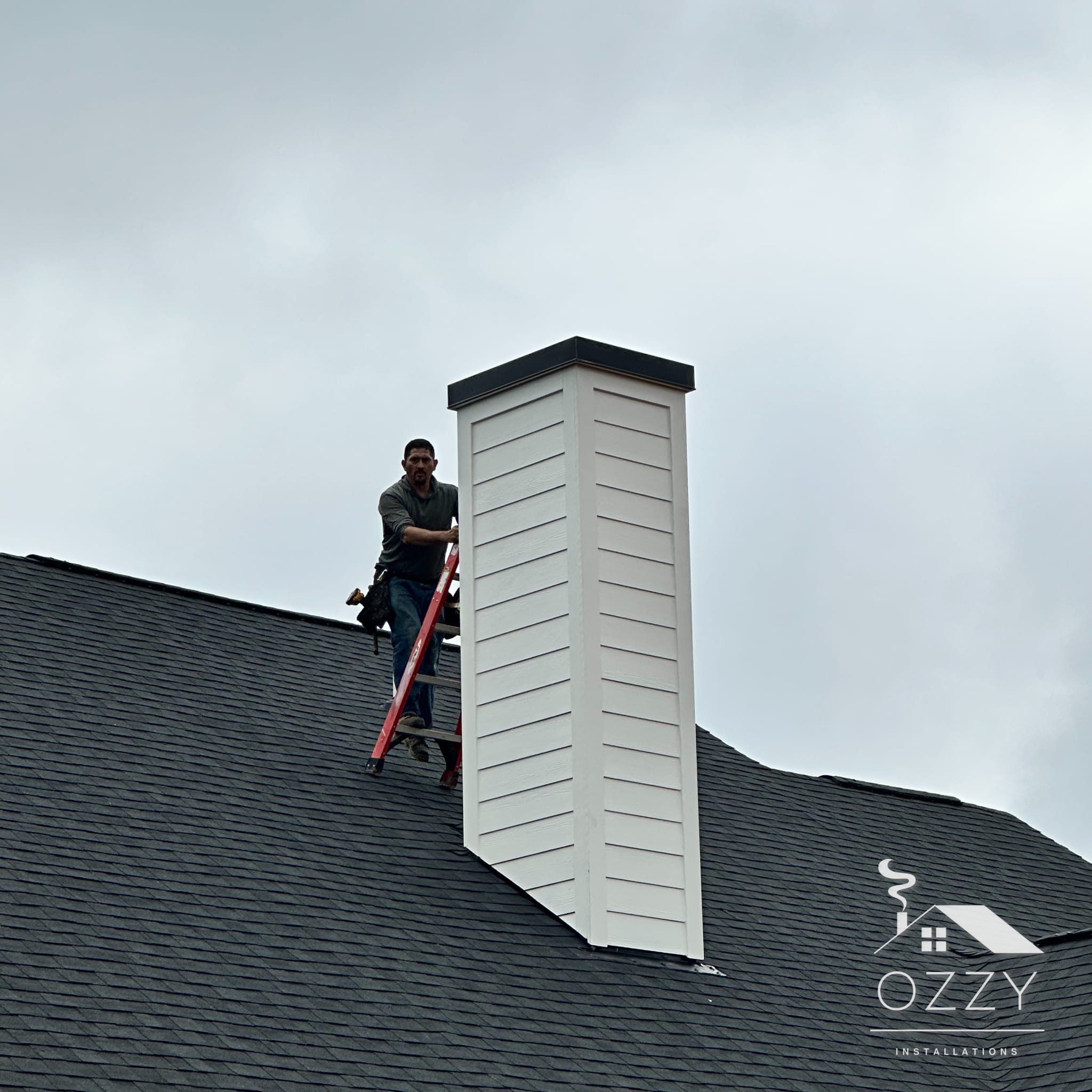 Ozzy Installations crew member on a roof beside a newly finished chimney chase