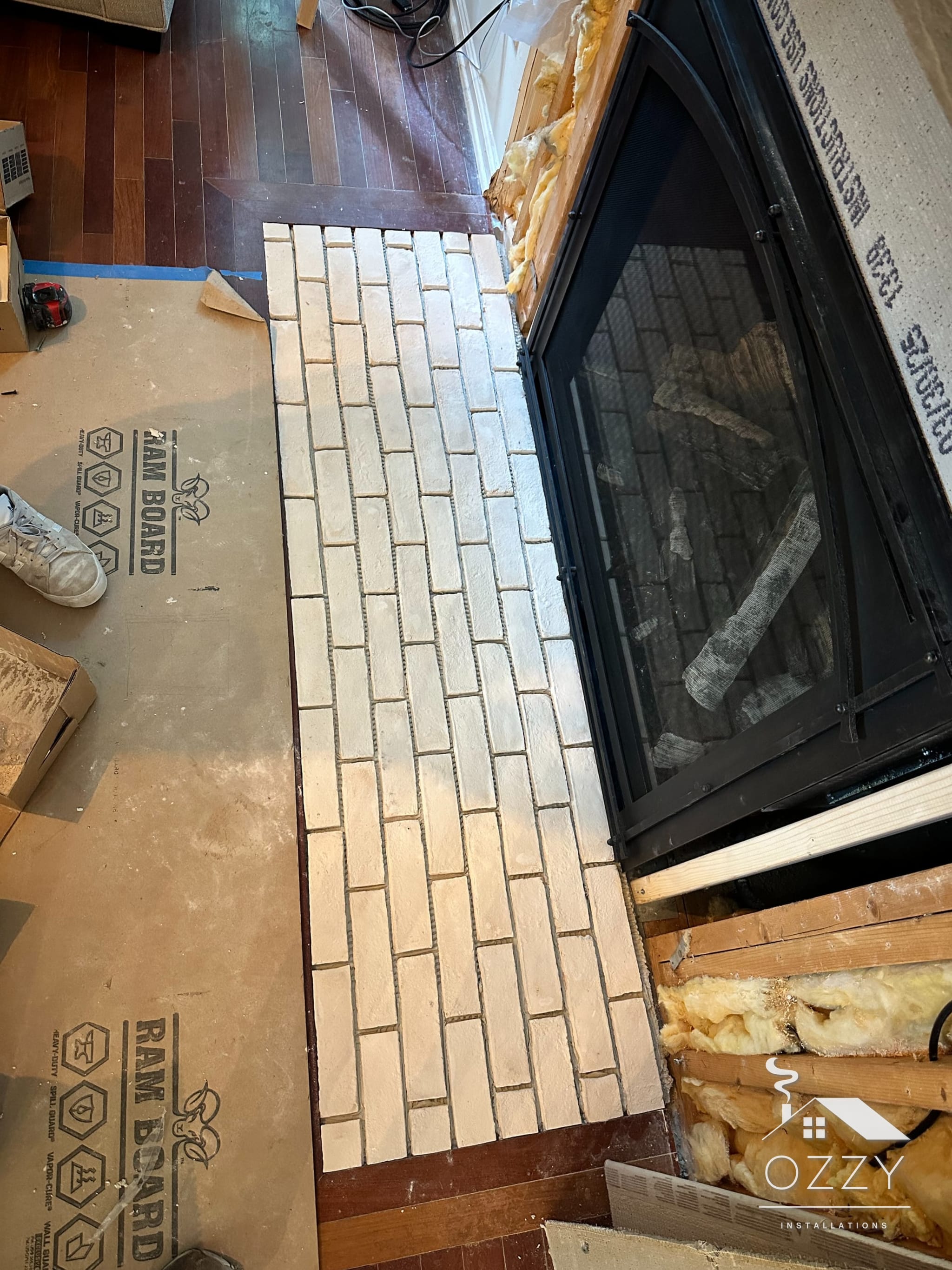 Whitewashed brick being laid on the hearth beside the new fireplace