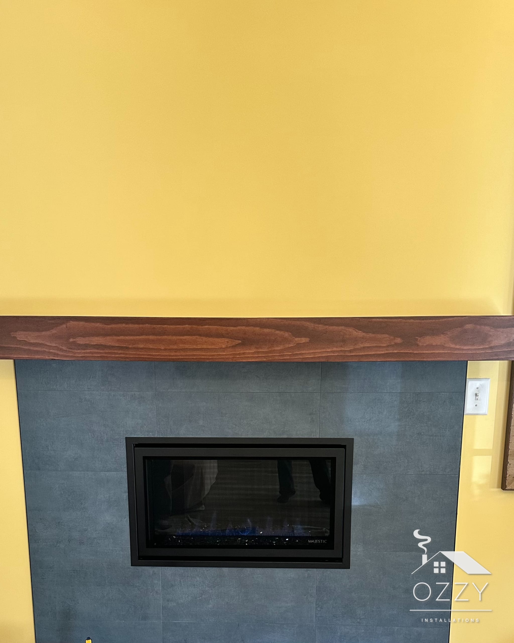 Linear gas fireplace in a slate tile surround under a wood mantel