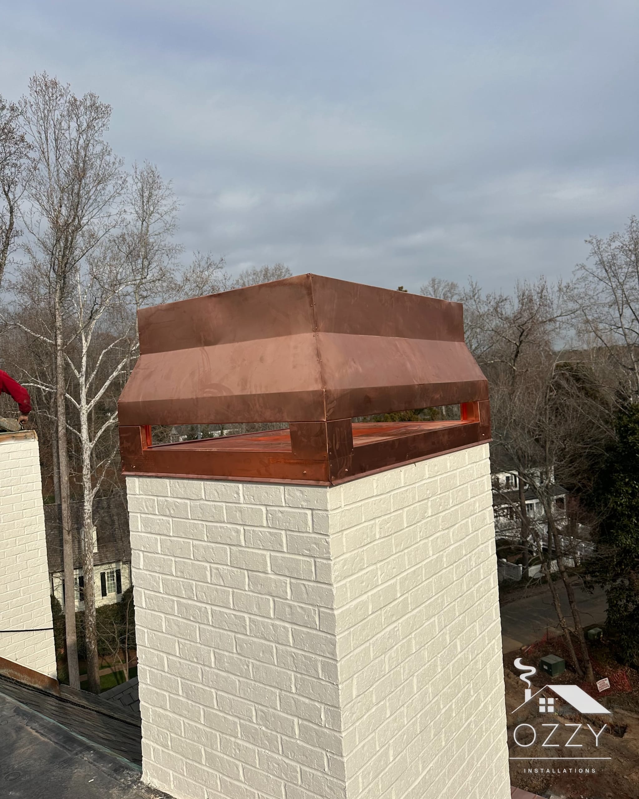 Copper chimney cap on a white painted brick chimney