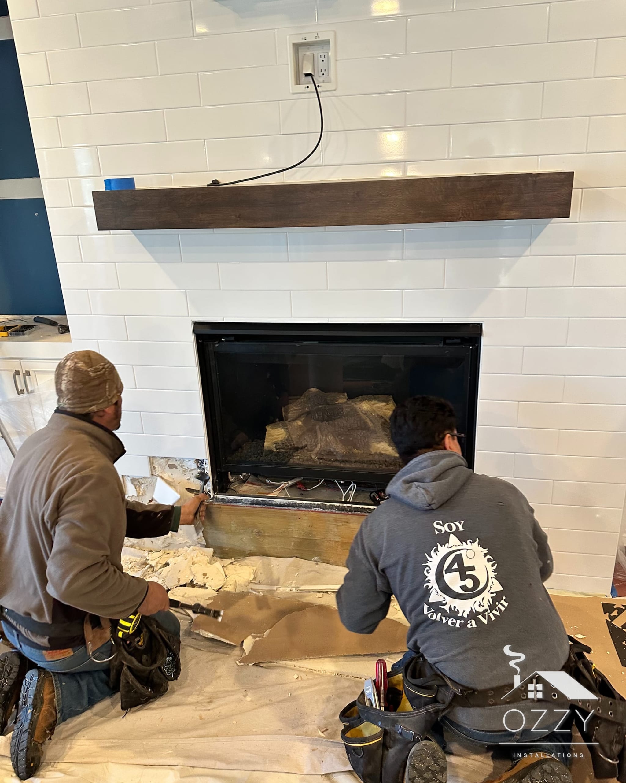 Crew members kneeling at a fireplace, fitting the surround