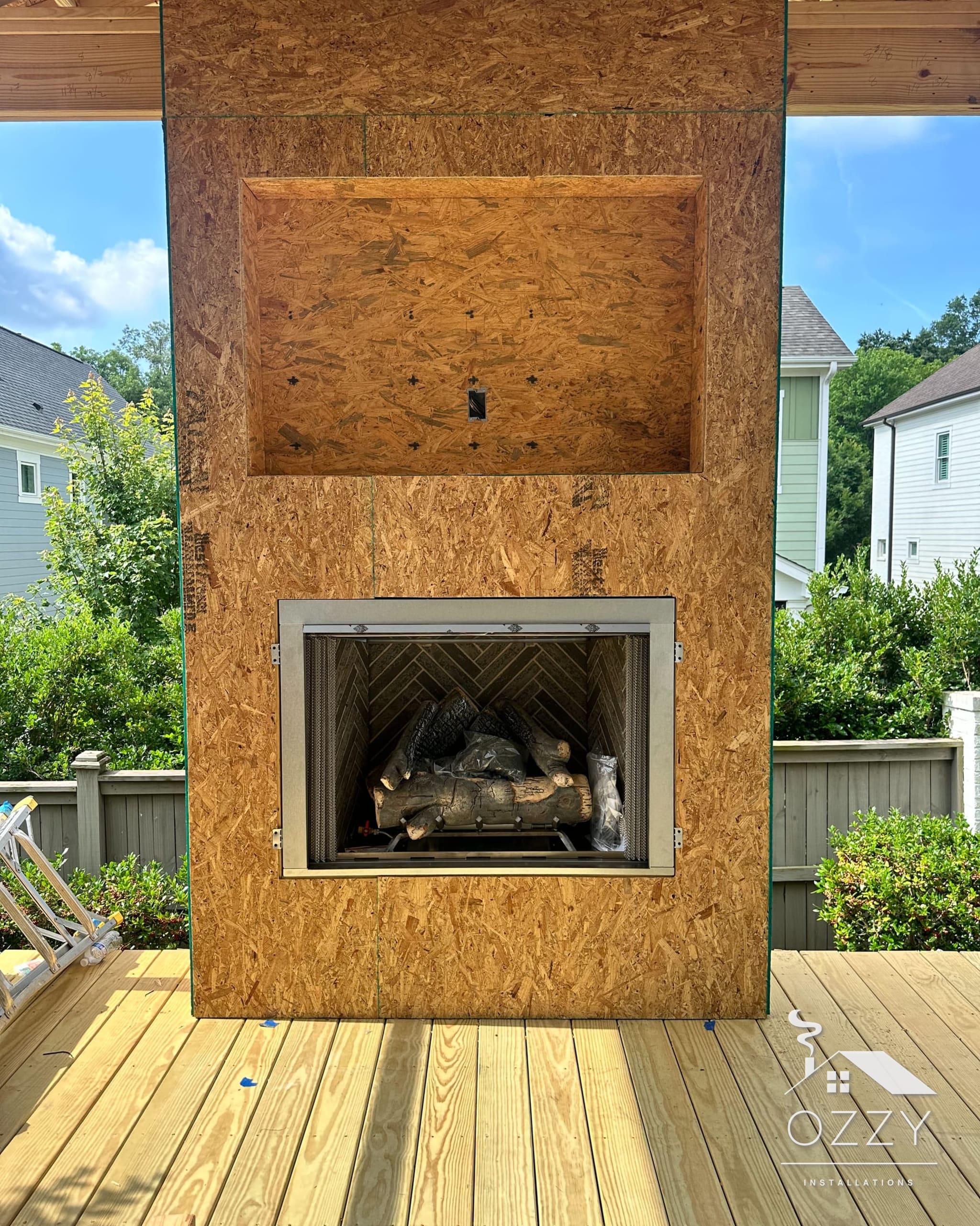 Outdoor fireplace with gas logs in a framed surround on a covered wood deck