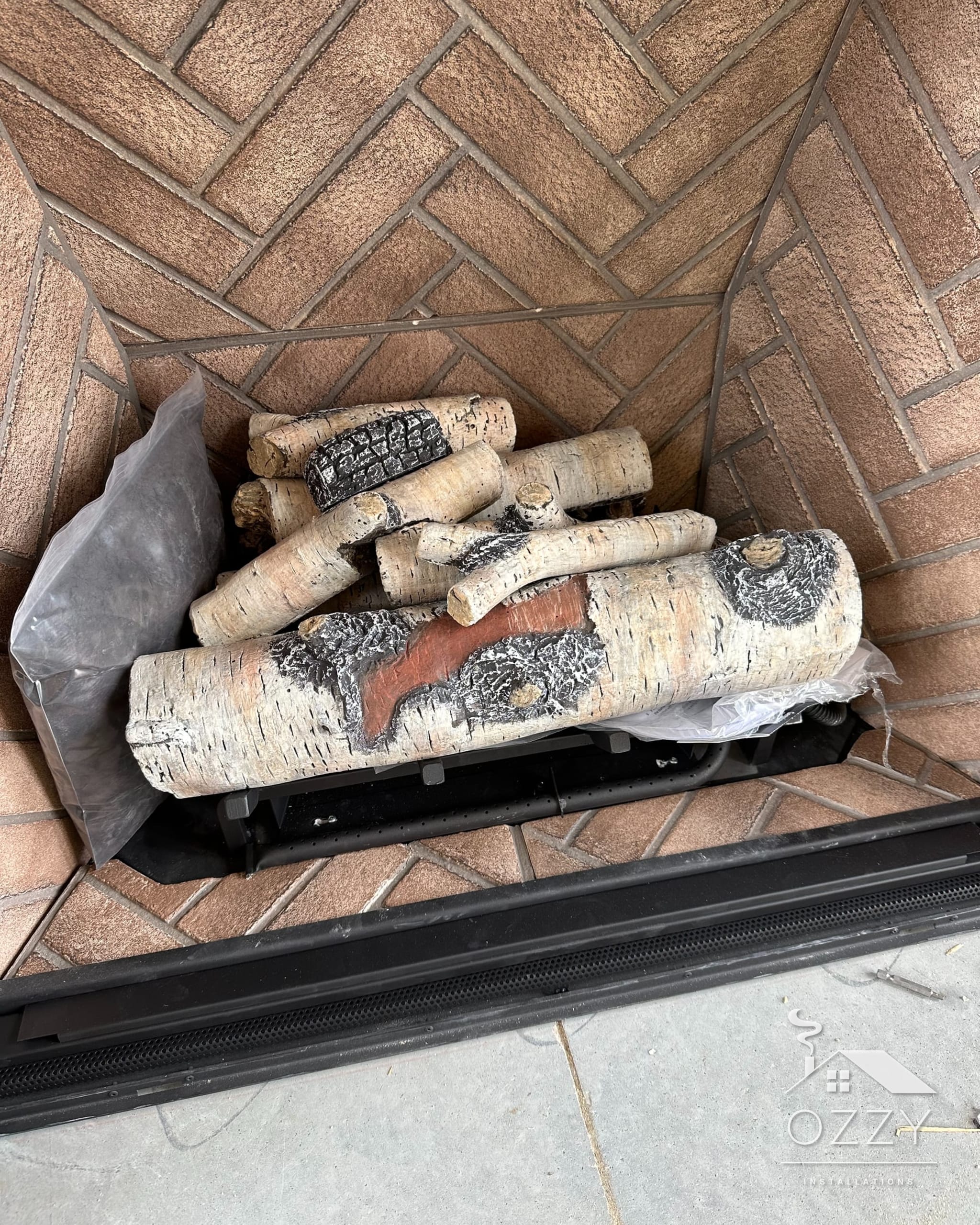 Firebox lined with firebrick in a herringbone pattern, with a gas log set