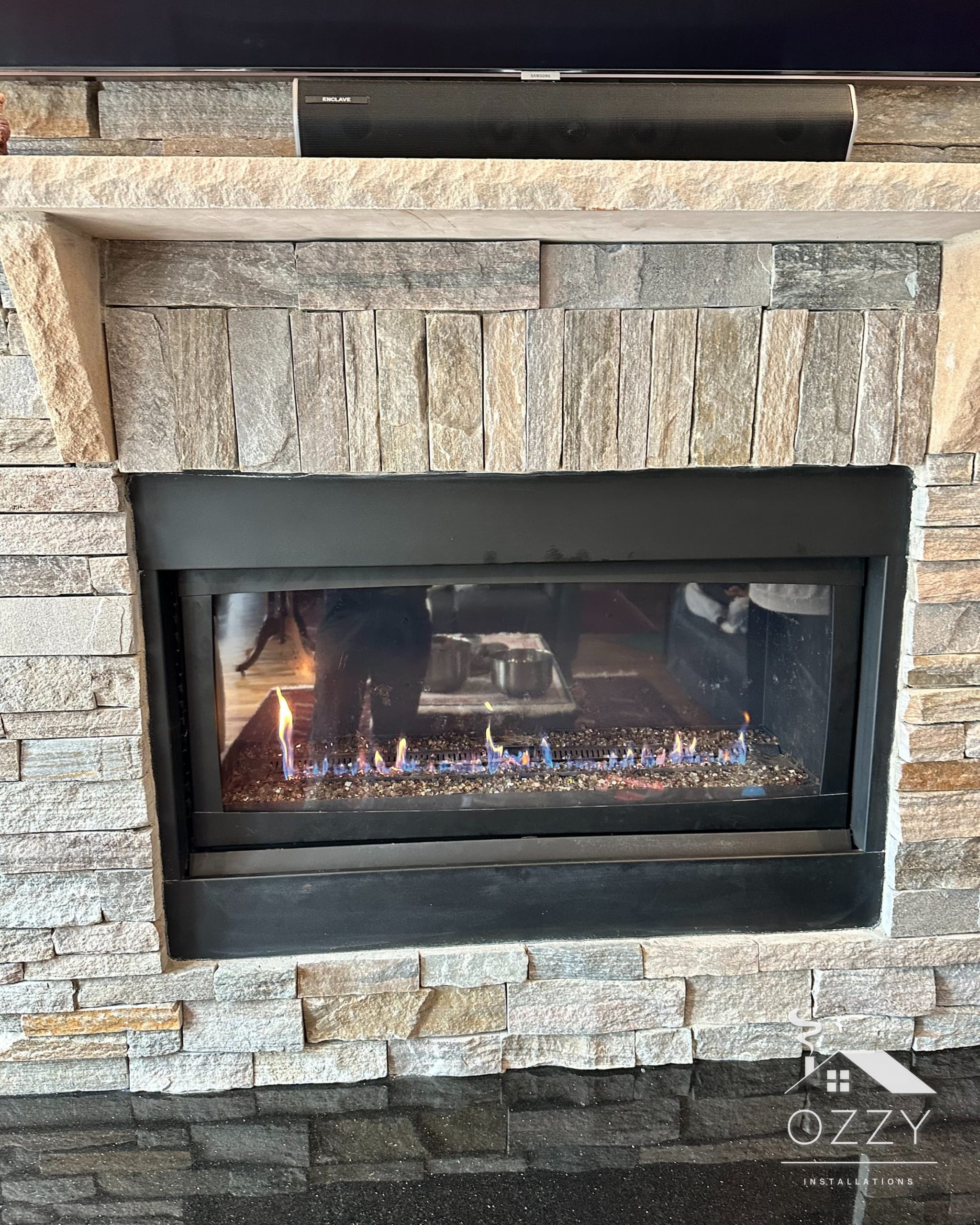 Linear gas fireplace with a flame running, set in a stacked stone wall