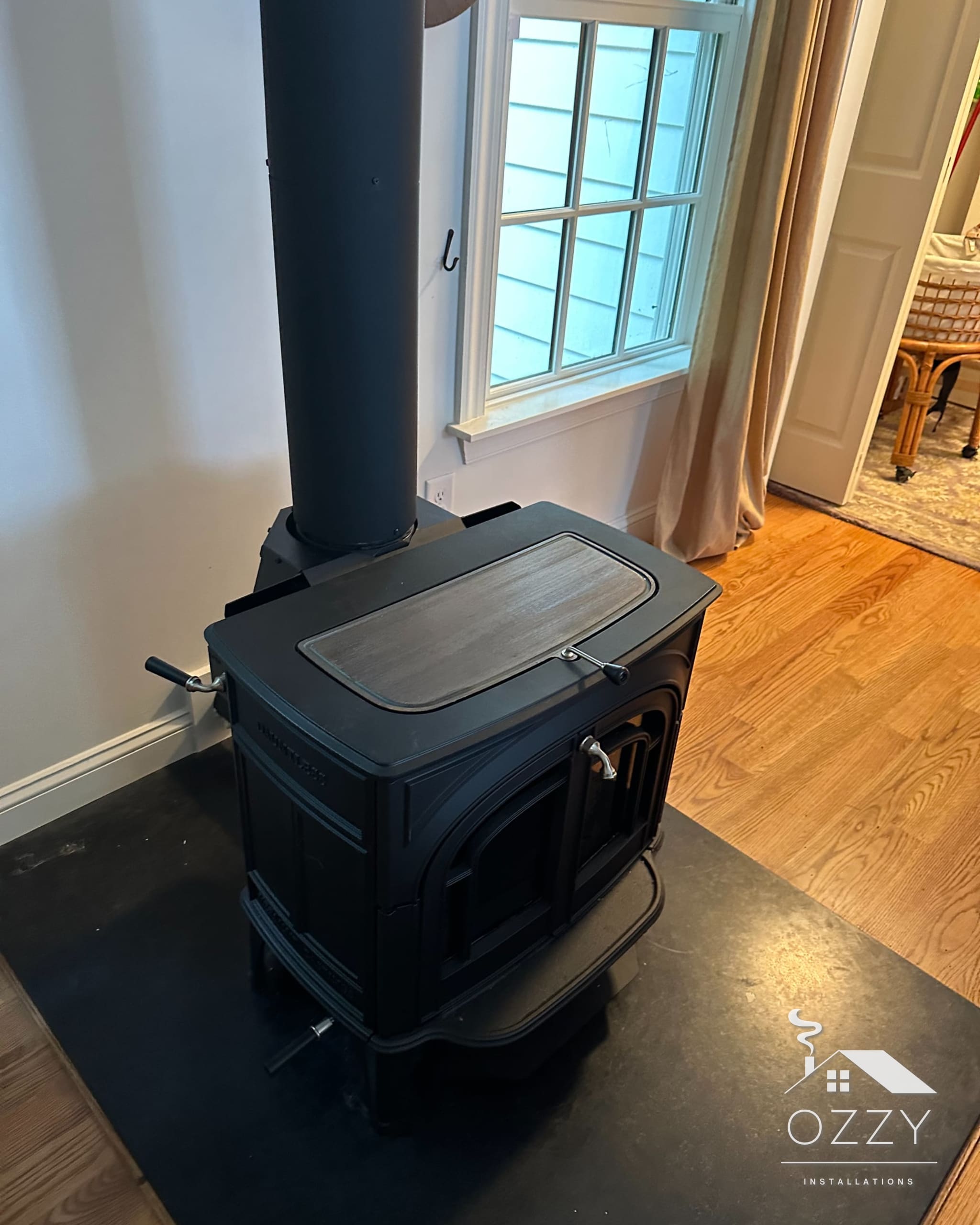 Black wood stove with stovepipe running up through the ceiling