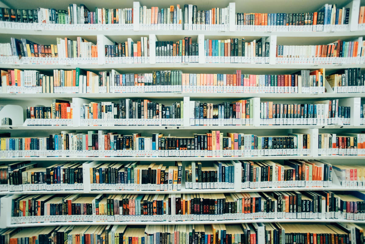 Wide shot of 8 shelves of library books of various colors and sizes.