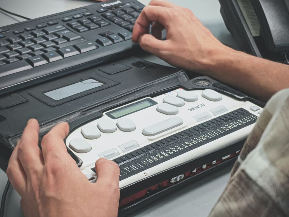 Low shot of someone using an adaptive keyboard setup to access their laptop computer.