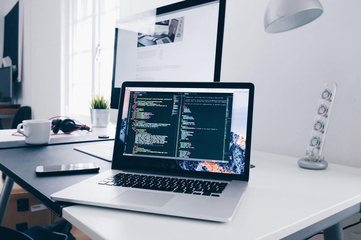 TypeScript developer job description | A laptop computer sitting on a desk with a speaker to the right and an external monitor in the background.