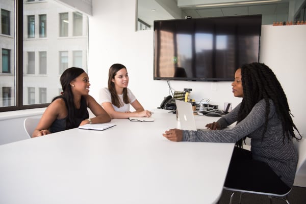 Three women sitting at a table conducting a job interview.