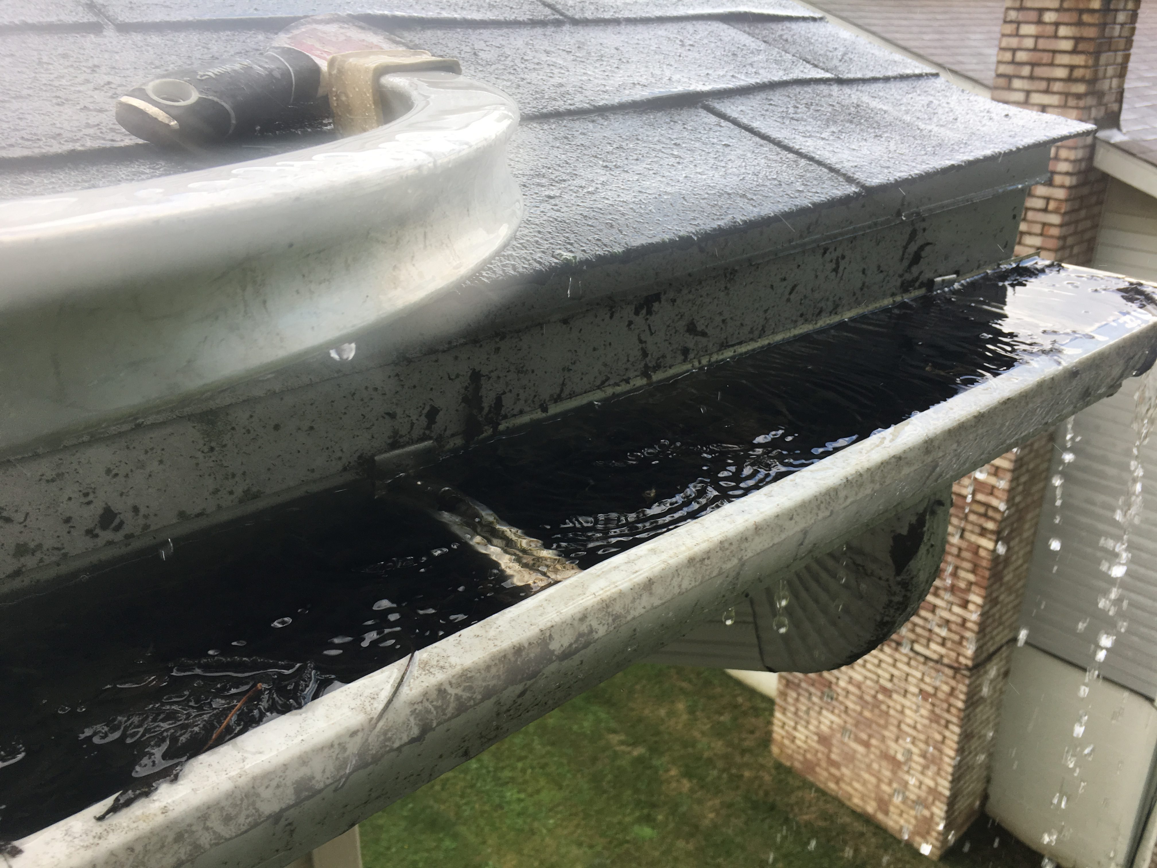 clogged gutters water to the brim and leaking over