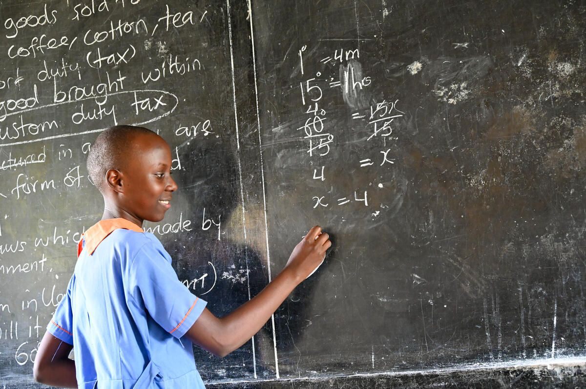 Sarah, 14, solving a math problem on the chalkboard in the classroom