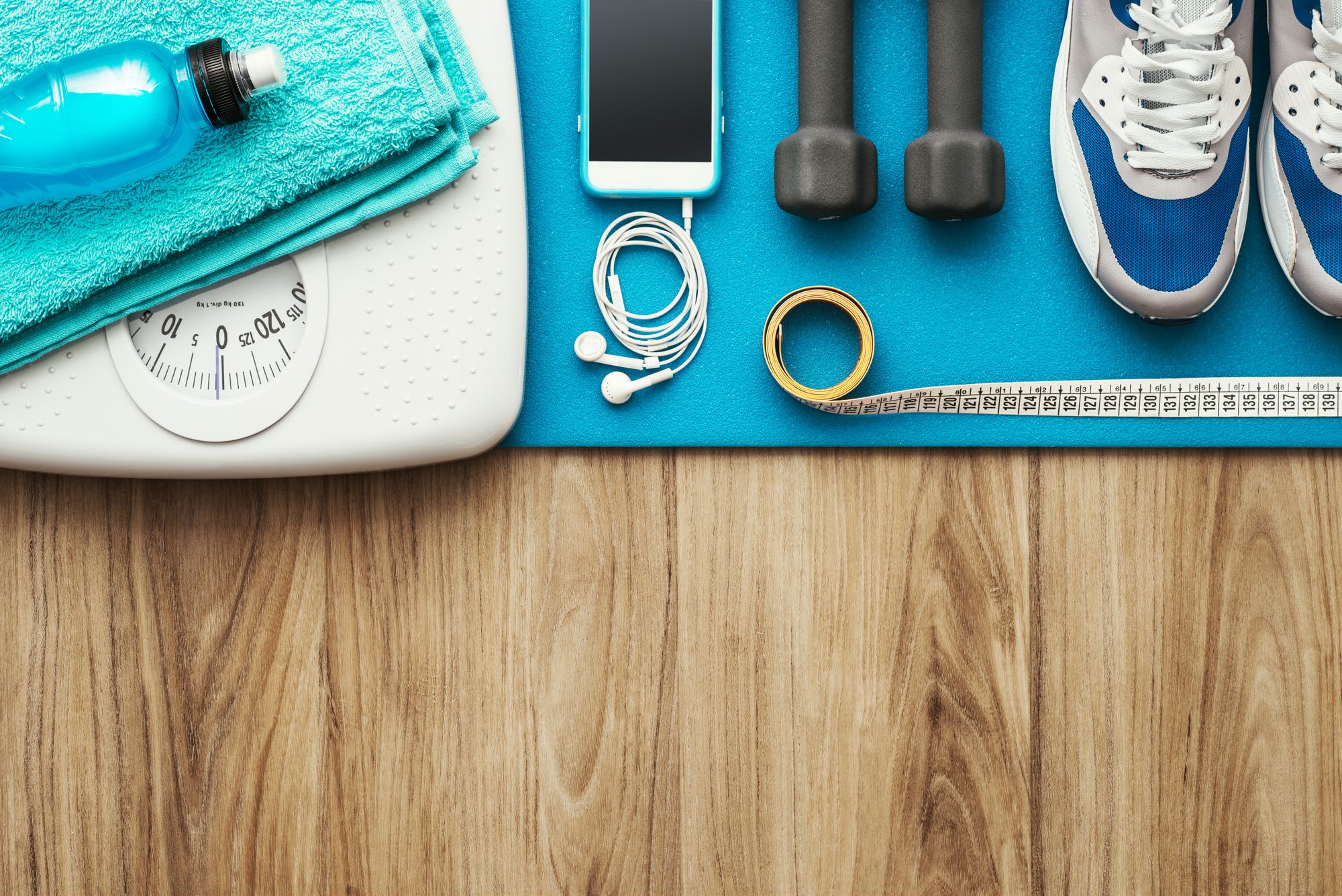 Accessoires fitness: balance, haltères, bouteille d"eau, écouteurs, mètre, chaussures, serviette.