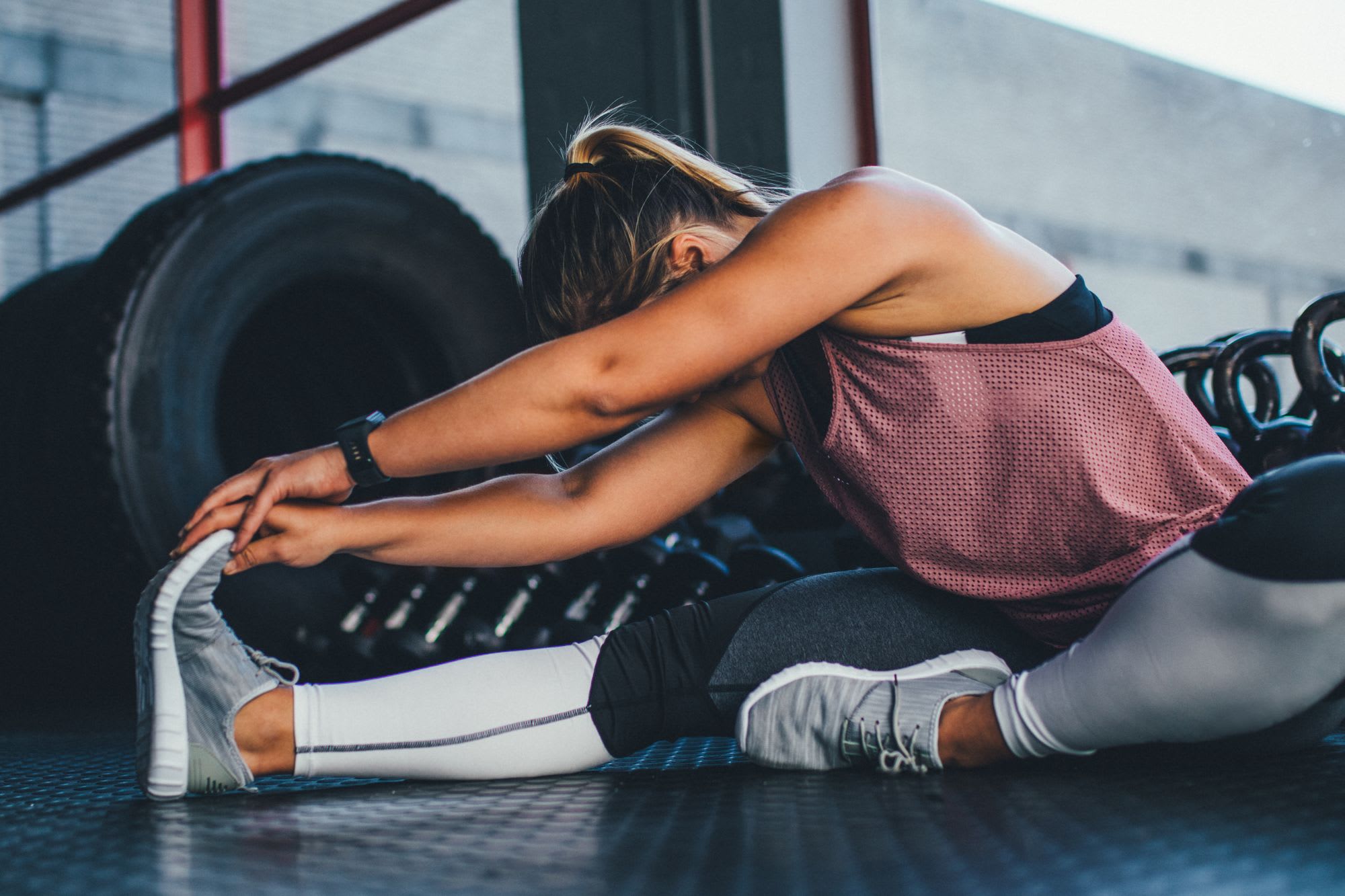 A girl sat stretching on the gym floor
