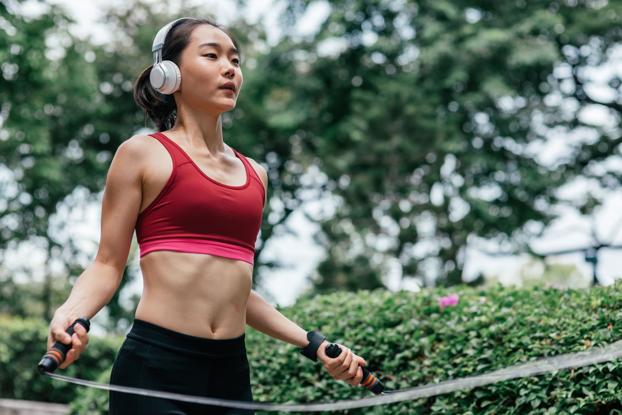 Fitness female doing skipping workout outdoors on a sunny day. Horizontal shot