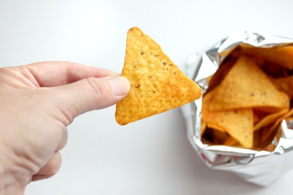 Hand in frame, snacking on corn chips straight out of the bag