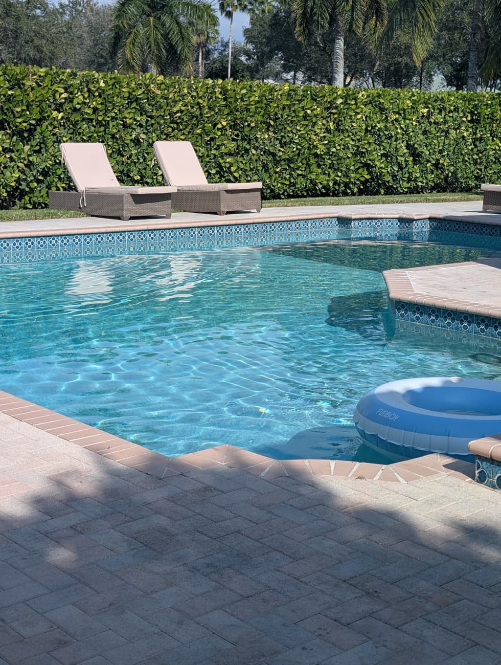 A pool technician cleaning a clear blue residential swimming pool