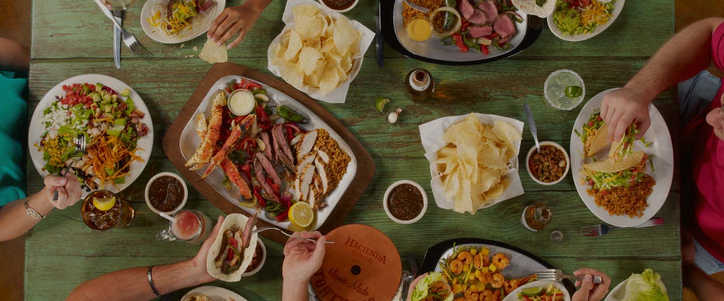 overhead shot of table with fajitas, drinks, chips and salda