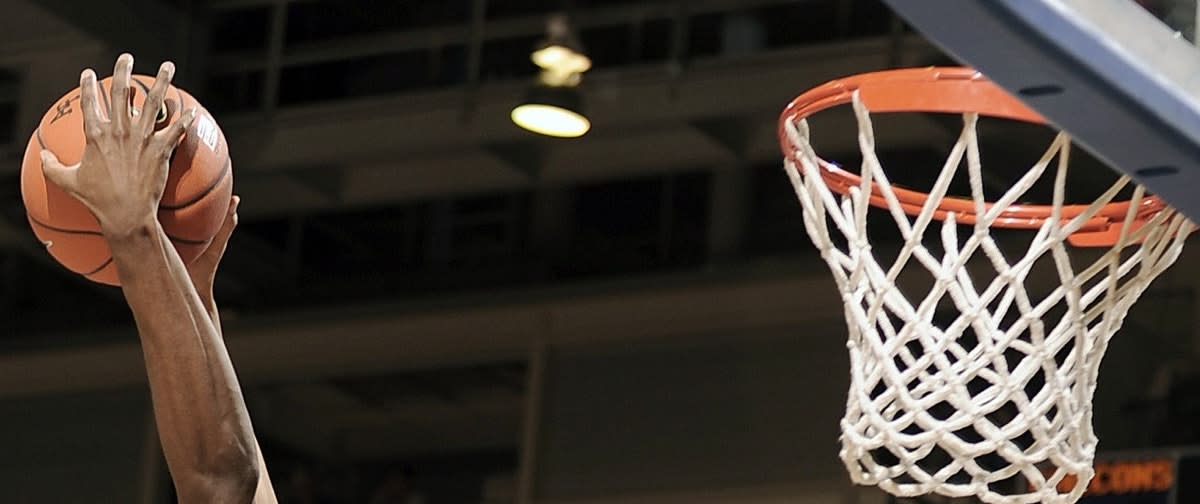 Hand with a basketball in it near a basketball net