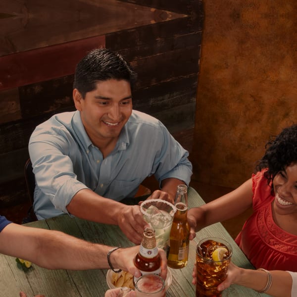 group of people cheers multiple drinks together inside