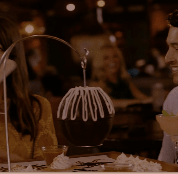 people sitting around a table with hanging chocolate pinata