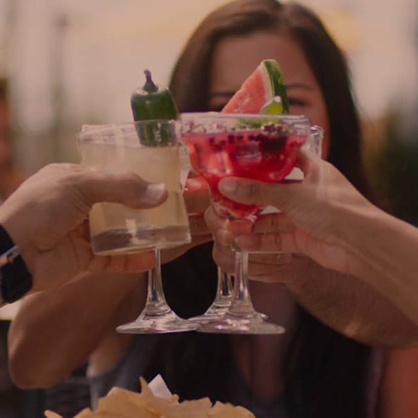 People cheers drinks while sitting on patio outdoors