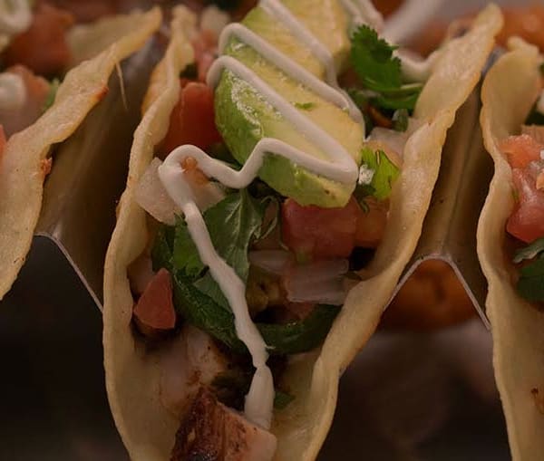 Three of Hacienda Colorado's Street Tacos on a platter with tomato, cilantro and avocado