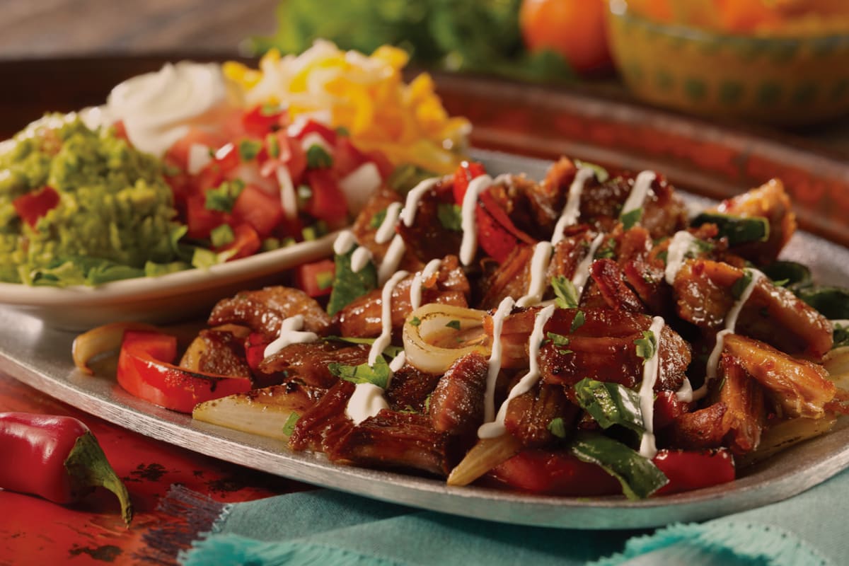 carnitas fajitas served on plate with side of fresh guacamole