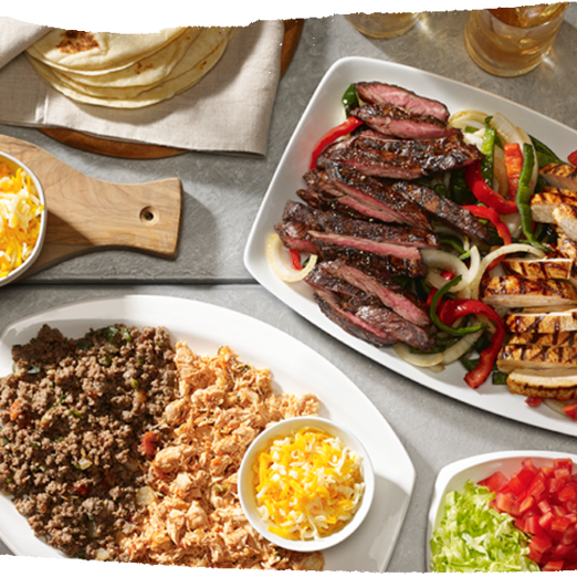 overhead shot of table with fajita meat, ground beef and chicken, and tortillas