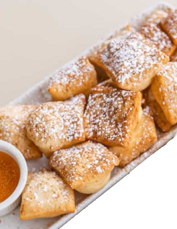 Powdered sopapillas served with a side of honey for dipping