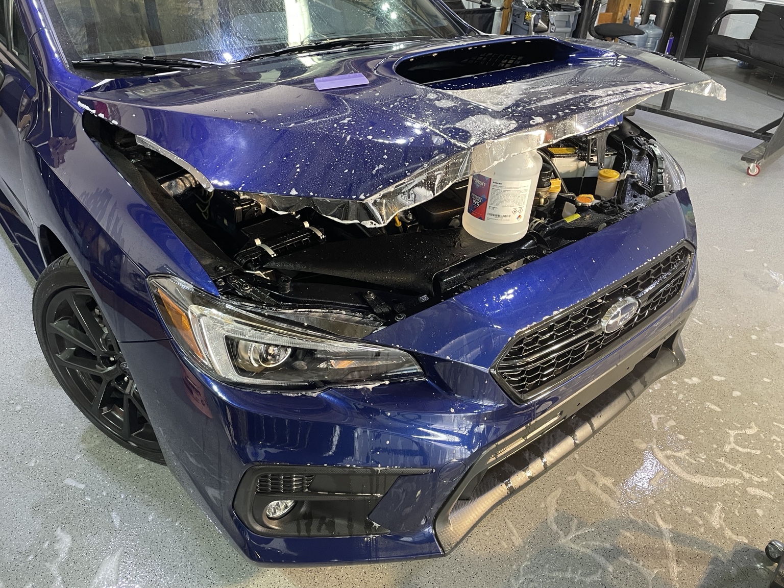Paint protection film installation on the hood of a blue Subaru WRX
