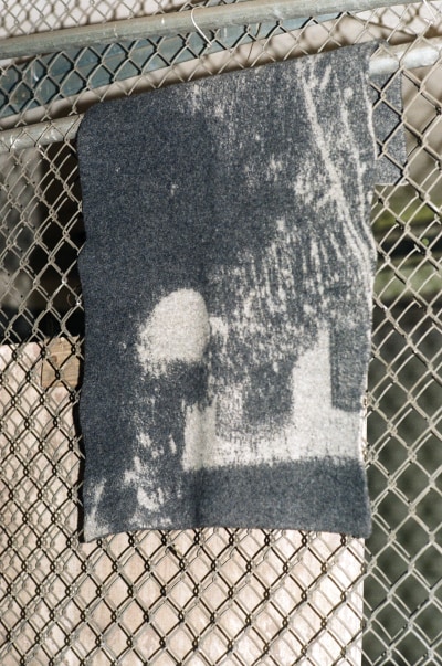half-wet low res rugs grey felted Spectral Orb rug hanging from a fence. photo by Christian Michael Filardo