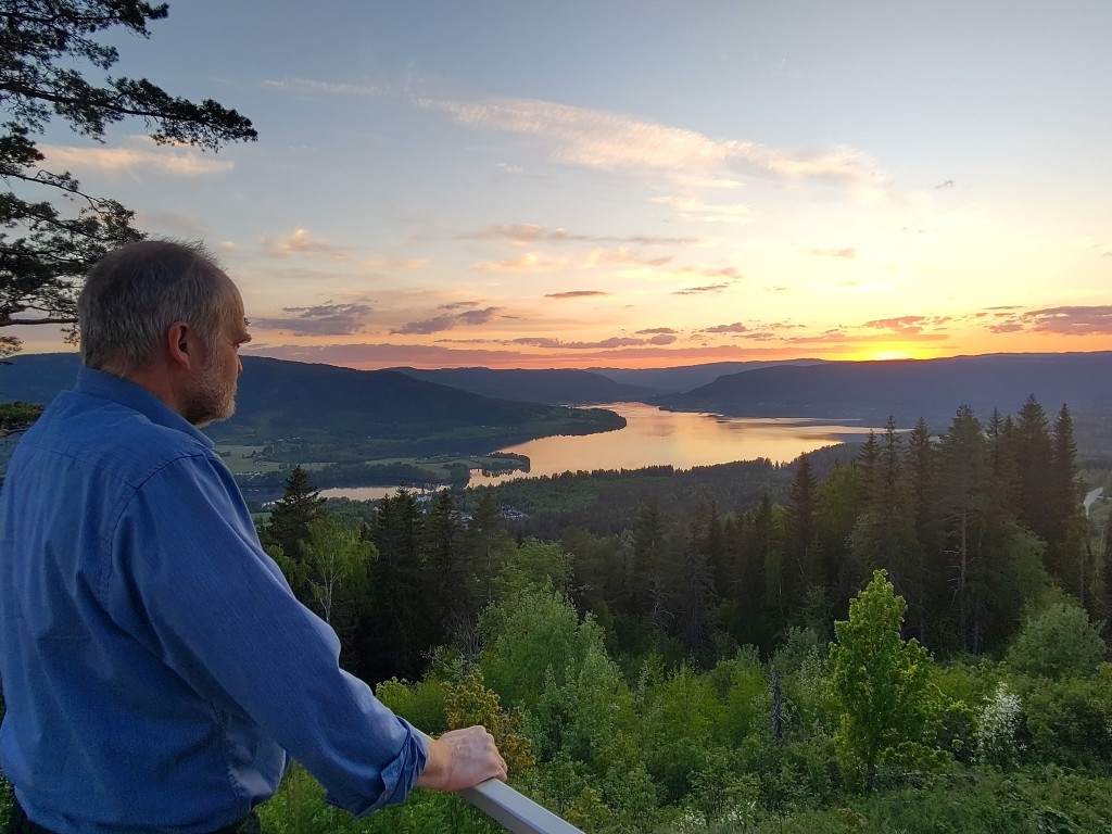 Vertskapet nyter kveldshimmelen over Randsfjorden sett fra terassen på pensjonatet her på Granum. Dokkadeltaet Våtmarksområde sees innerst i fjorden.