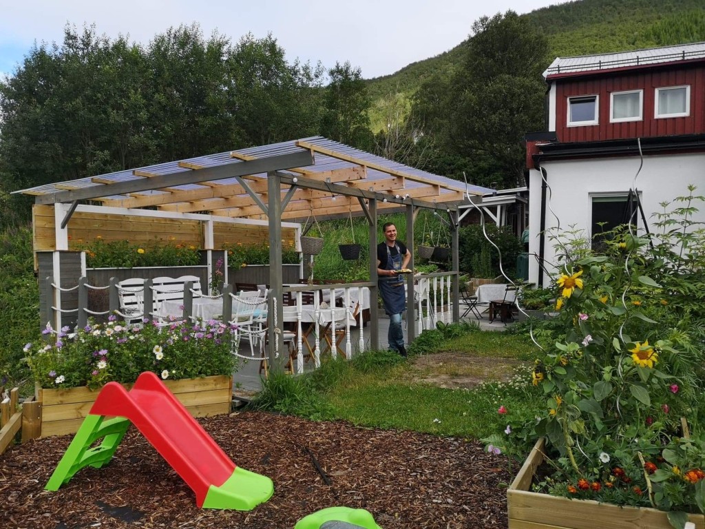 I hagen vår kan du sitte og spise under tak, og til de minste barna har vi et lite lekeområde