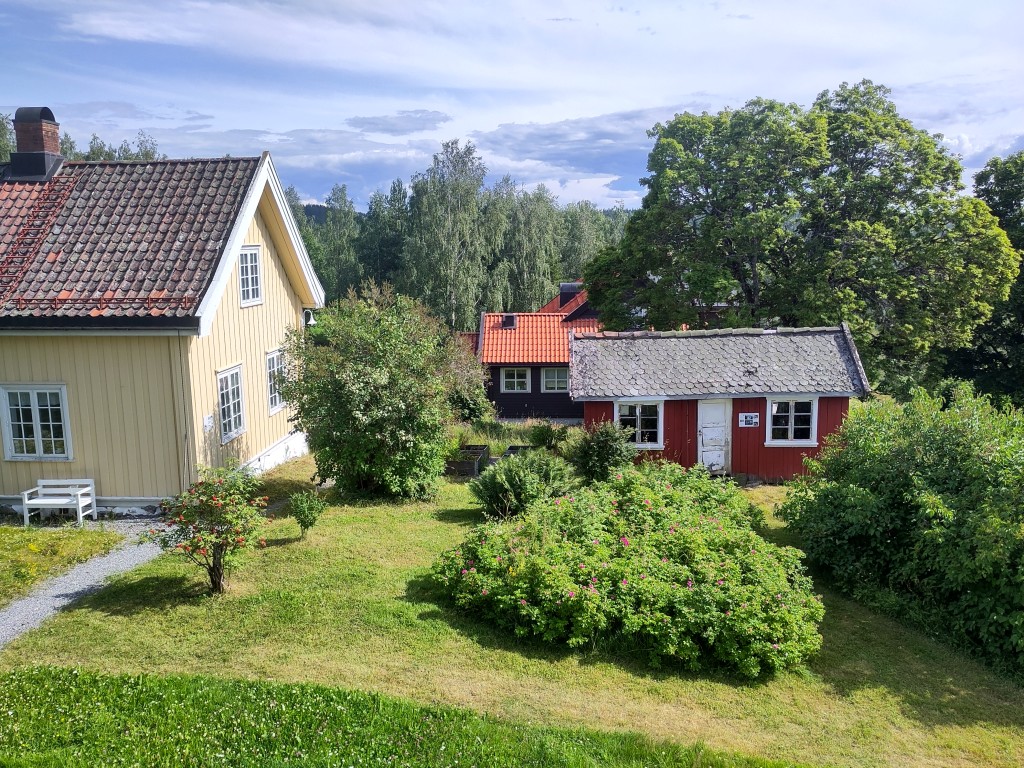 Utsikt til hagen fra andre etasje i pensjonatet. Her ser du den gule kårstua og den røde dokkestua. Dokkestua var opprinnelig utedo for de tyske soldatene under krigen, men ble flyttet opp på tunet og omgjort til dokkestue etter at tyskerne bygde bunkeren og ny utedo der.
