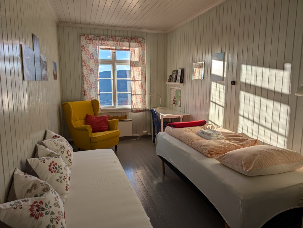 Rom nr 2: Ridevegen: Enkeltrom med en ekstraseng. Flere av møblene her er laget på snekkerverkstedet på gården og lenestolen er i 50 talls stil. Utsikt mot Randsfjorden. Temaet her er den eldgamle ferdselsåra Ridevegen som går gjennom tunet vårt.