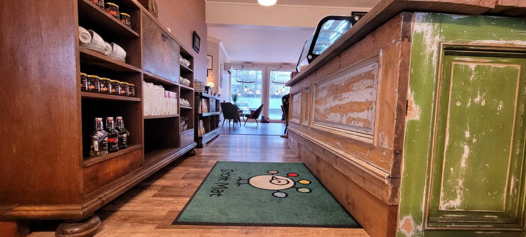 Inngang fra butikk til kafé, med disk laget av gamle dører fra et hus i Ålesund.