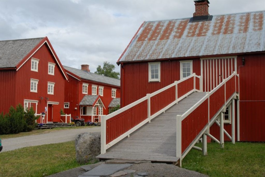 Velkommen til gårds! Bildet viser baksida av Gammellavin der restauranten holder til, og på bortersida av vegen ser de Buret (stabburet) der de finn bundaproduksjon og sommarutstilling.