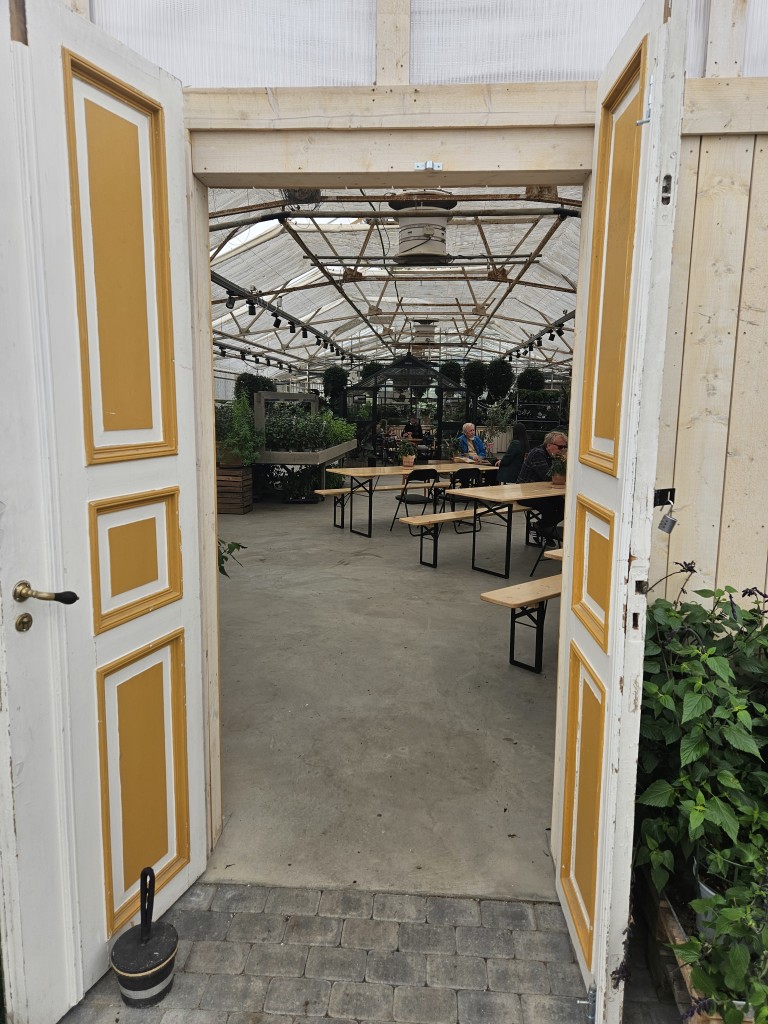 På en kjølig da er det menge som nyter kaffen og baksten inne i veksthuset mellom plantene.