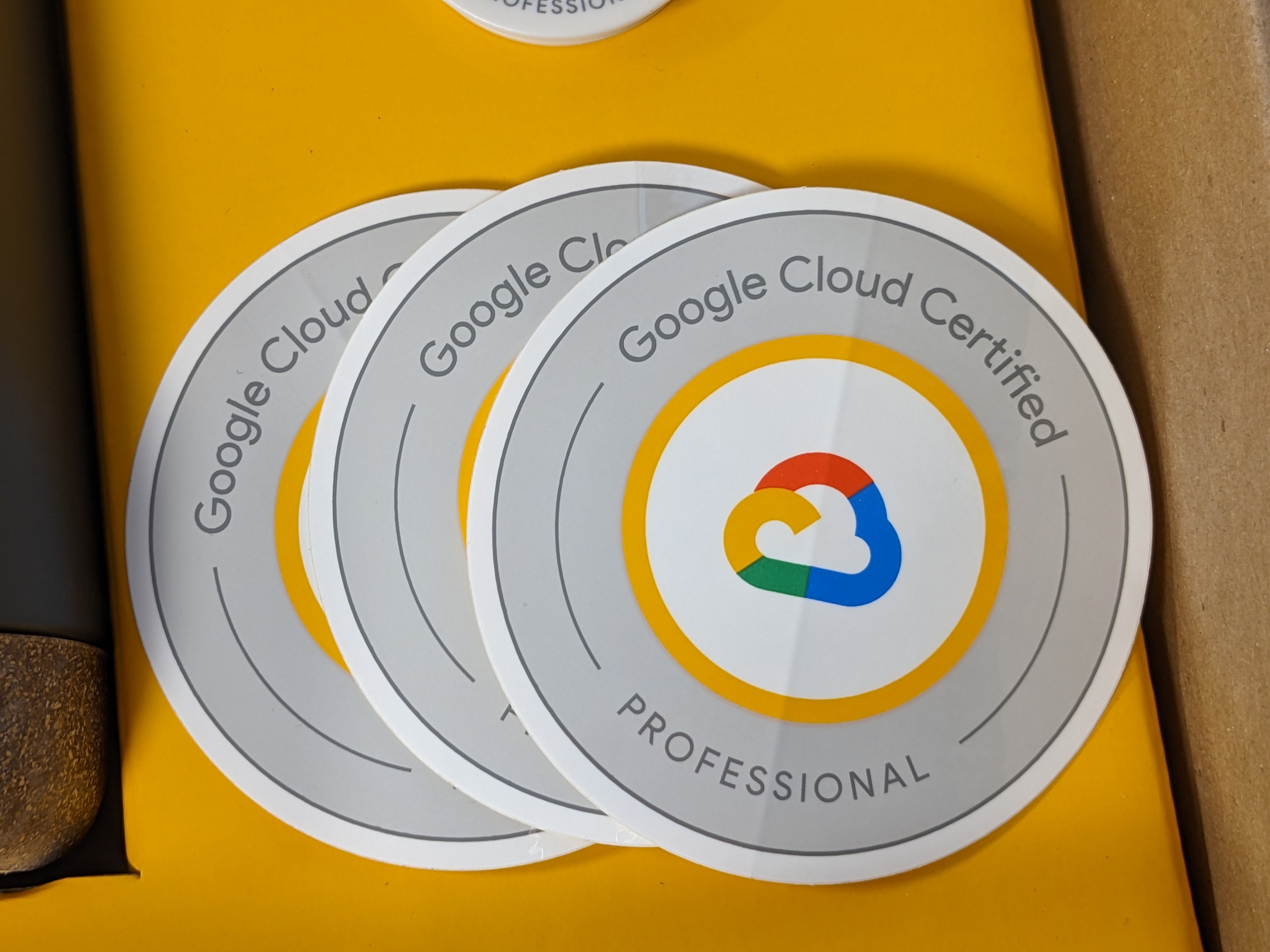 A close-up of three round, grey "Google Cloud Certified - PROFESSIONAL" stickers.