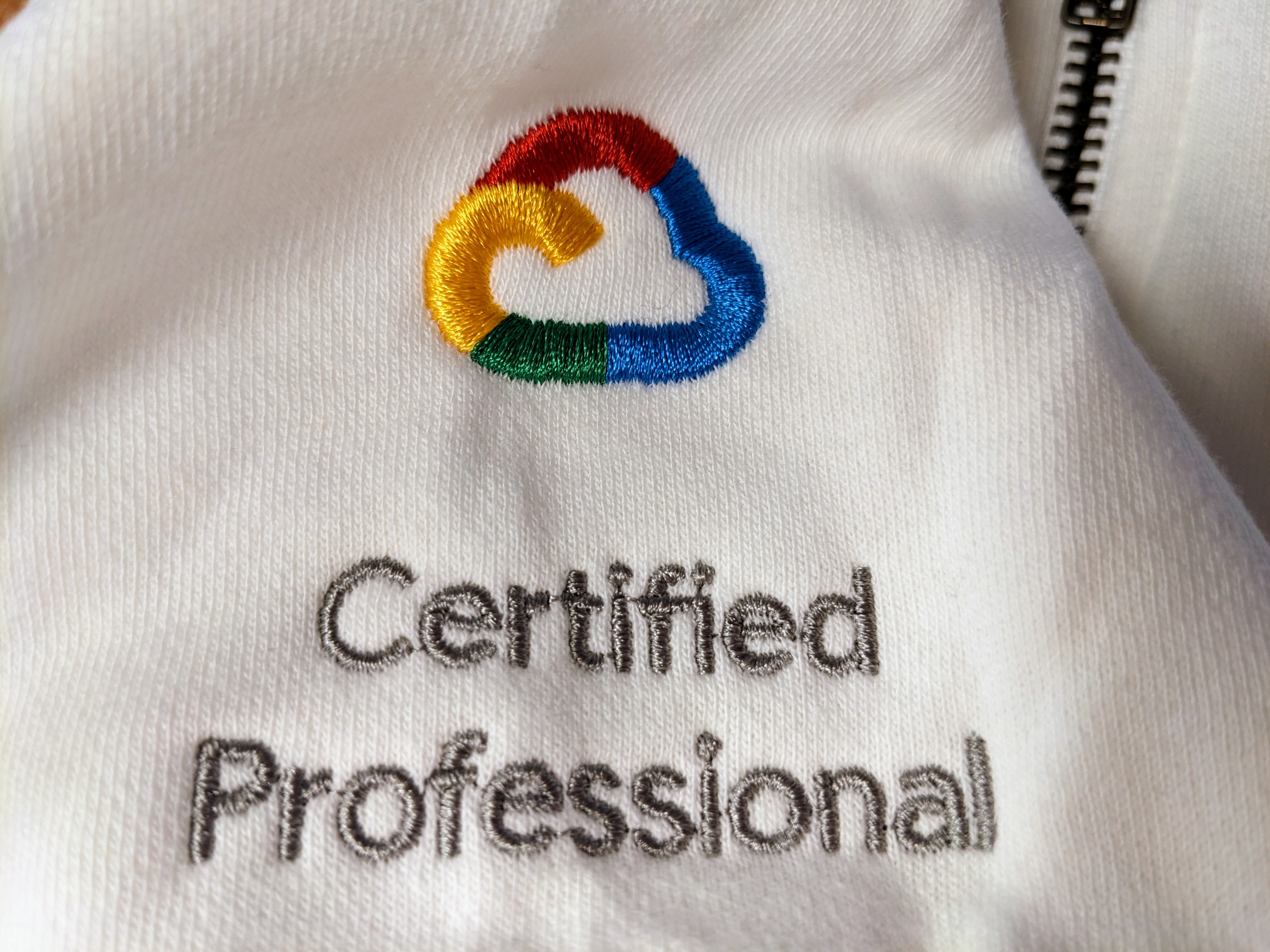 A close-up of the embroidered Google Cloud "Certified Professional" logo on a white zippered hoodie.